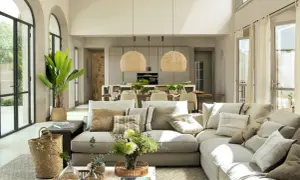 Sofá modular color topo, con cojines de texturas y tonos tierra, junto a una mesa de centro con cesta de mimbre y flores.