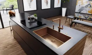 Cocina moderna con isla, placa de inducción y fregadero de cobre. Varios tipos de fregaderos, como este de diseño, realzan la estética.