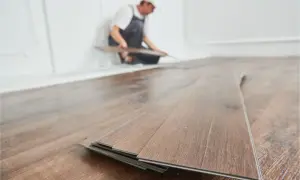 Instalador colocando tablas de vinilo SPC en un suelo de madera.