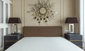 Un espejo sol y lámparas oscuras sobre mesitas de noche grises ayudan a alegrar una habitación con muebles oscuros.