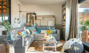 Acogedor salón con sofá gris, cojines coloridos y alfombra étnica. Un espacio que demuestra que las sencillas salas pequeñas pueden ser muy estilosas.