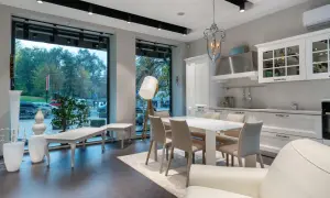 Espaciosa cocina salón comedor de 30 m2 con isla, mesa y sillas, sofá blanco y gran ventanal.