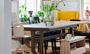 Un banco almacenaje de madera clara, perfecto para guardar libros y objetos, complementa la mesa de comedor.