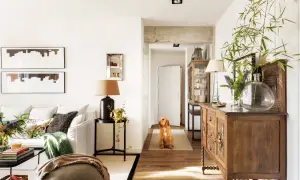 Un perro espera en el pasillo que conecta el salón y la entrada. Muebles antiguos y plantas decoran el espacio.
