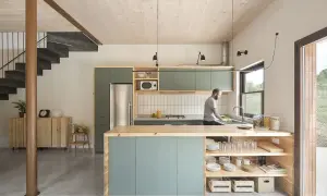 Hombre lavando platos en una cocina moderna y luminosa, ideal para renovar cocina con estilo minimalista y materiales naturales.