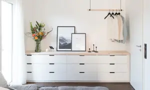 Ideas para decorar cómoda dormitorio matrimonio: ramo de flores, cuadros, velas y ropa colgada.