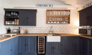 Cocina reformada sin obras: armarios azul marino, encimera de madera, fregadero blanco y suelo de baldosas a cuadros.