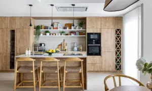 Cocina moderna con armarios de madera clara, isla central con taburetes y estanterías decoradas. Ideal para inspiración de decoracion cocinas.