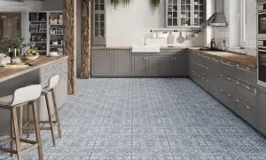 Cocina moderna con suelo hidráulico de diseño geométrico en tonos grises y blancos. Muebles de cocina grises, encimera de madera y barra americana con taburetes.