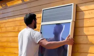 Hombre instala panel solar para calefacción en pared de madera.