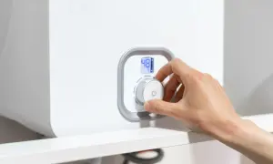 Mano girando el dial de la caldera para subir la presión. La pantalla digital muestra 48°C.