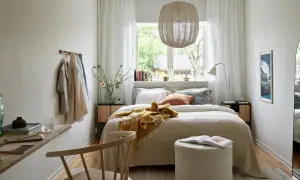 Acogedora cama bajo ventana, con manta amarilla y cojines. Ideas para un dormitorio luminoso y funcional.