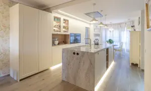 Cocina moderna con isla central de granito, gabinetes blancos y suelo de madera. Una guía visual sobre como distribuir una cocina funcional y elegante.