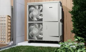 Unidad exterior de bomba de calor, eficiente en su caldera eléctrica consumo, instalada junto a una valla de madera y vegetación.