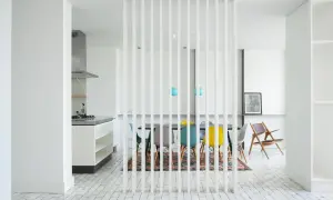 Elegante divisor vertical para dividir salón en dos ambientes, separando la cocina de la zona de comedor con sillas de colores.