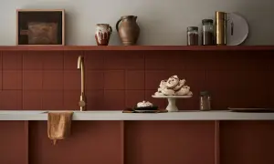 Encimera de cocina pintada en tono terracota, con grifería dorada y detalles decorativos.
