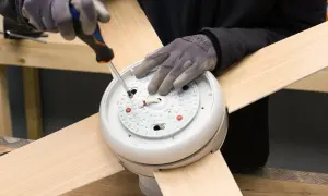 Manos enguantadas atornillan el motor de un ventilador de techo.