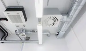 Sistema de ventilación mecánica para vivienda con conductos metálicos, unidades de aire acondicionado y luces LED en el techo.