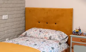 Cabecero tapizado en pana mostaza, ideal para aprender como tapizar un cabecero. Cama con ropa de cama infantil y mesita de noche.
