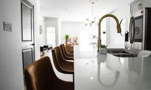 Una moderna cocina abierta con barra de desayuno, sillas de cuero y electrodomésticos de acero inoxidable.