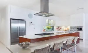 Cocina moderna con isla, nevera de acero inoxidable y campana extractora. Ideal para tu reforma cocina precio.