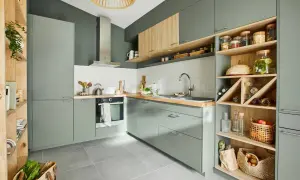 Moderna cocina verde y madera con estanterías abiertas llenas de botellas, cestas y tarros.