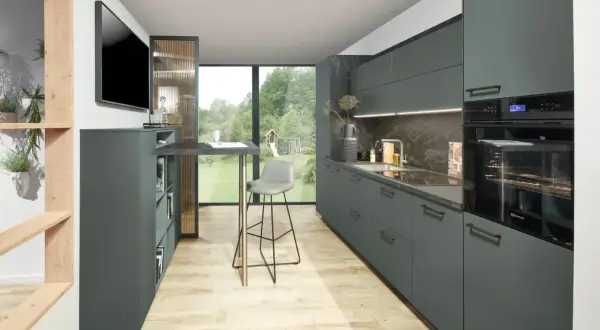 Cocinas modernas con armarios grises, encimera de piedra y suelo de madera clara. Un taburete alto gris junto a una barra.