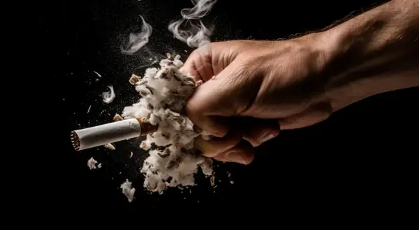 Puño aplastando un cigarrillo con humo, simbolizando cómo quitar el olor a tabaco de la casa.