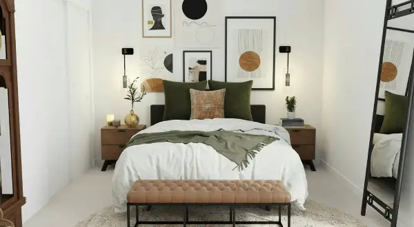 Habitación pequeña con cama grande, decorada con arte abstracto y cojines verdes. Un banco de terciopelo marrón al pie de la cama.