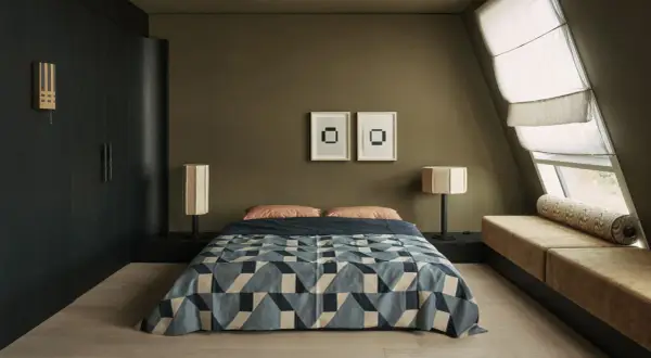 Dormitorios pequeños con cama geométrica, lámparas de diseño y un banco tapizado junto a la ventana.