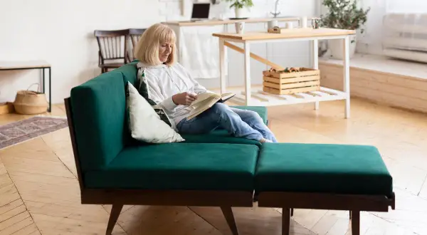 Mujer lee en un sofá modular verde, un ejemplo de muebles que se transforman para adaptarse a tu espacio y estilo de vida.
