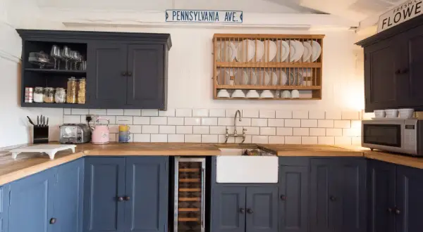 Cocina reformada sin obras: armarios azul marino, encimera de madera, fregadero blanco y suelo de baldosas a cuadros.