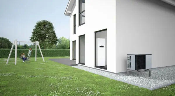 Casa moderna con jardín y columpio. Se ven bombas de calor para pisos, una unidad exterior y otra interior, garantizando confort y eficiencia.