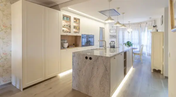 Cocina moderna con isla central de granito, gabinetes blancos y suelo de madera. Una guía visual sobre como distribuir una cocina funcional y elegante.