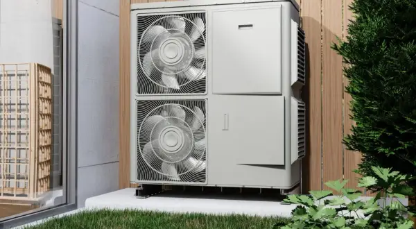 Unidad exterior de bomba de calor, eficiente en su caldera eléctrica consumo, instalada junto a una valla de madera y vegetación.