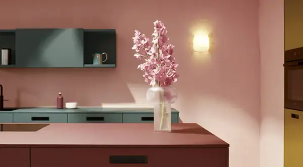 Elegante cocina con encimeras y armarios en tonos rosados y verde azulado. Un jarrón con flores rosas ilumina el espacio, creando una hermosa **combinación de colores para cocina**.