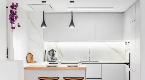 Cocina moderna y funcional, ideal para reformas de cocinas pequeñas. Muebles blancos, encimera de madera y detalles en mármol.