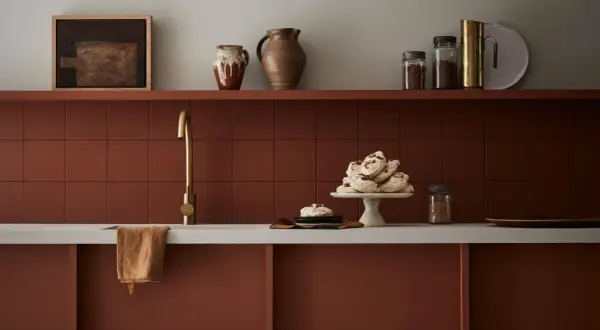 Encimera de cocina pintada en tono terracota, con grifería dorada y detalles decorativos.