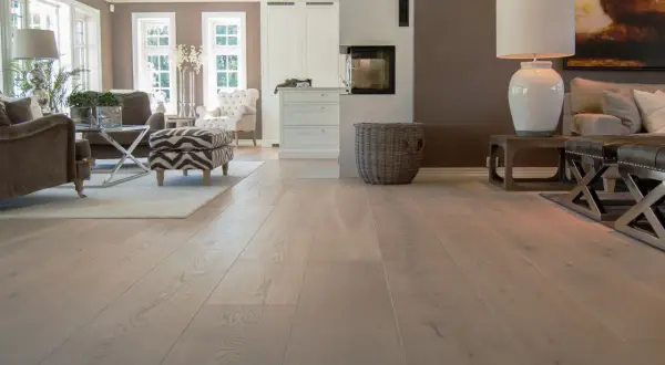 Amplio salón con chimenea y muebles elegantes, destacando los diversos tipos de parquet de madera clara que cubren el suelo.