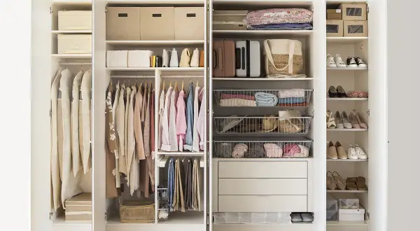 Armario organizado con ropa colgada y doblada, cestas y cajas, siguiendo el método Marie Kondo para un espacio ordenado y funcional.