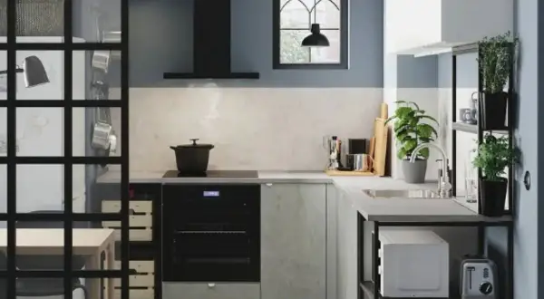 Cocina estrecha y pequeña con electrodomésticos modernos, plantas y una ventana con rejas.