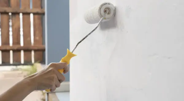Mano aplica imprimación pintura pared con rodillo.