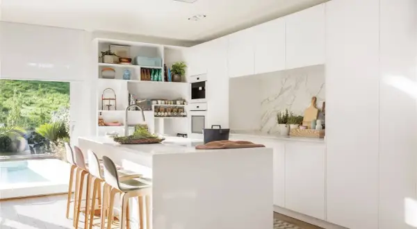 Cocina moderna y luminosa con isla central, taburetes y estanterías. Ideas de diseño cocina minimalista y funcional.