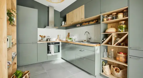 Moderna cocina verde y madera con estanterías abiertas llenas de botellas, cestas y tarros.
