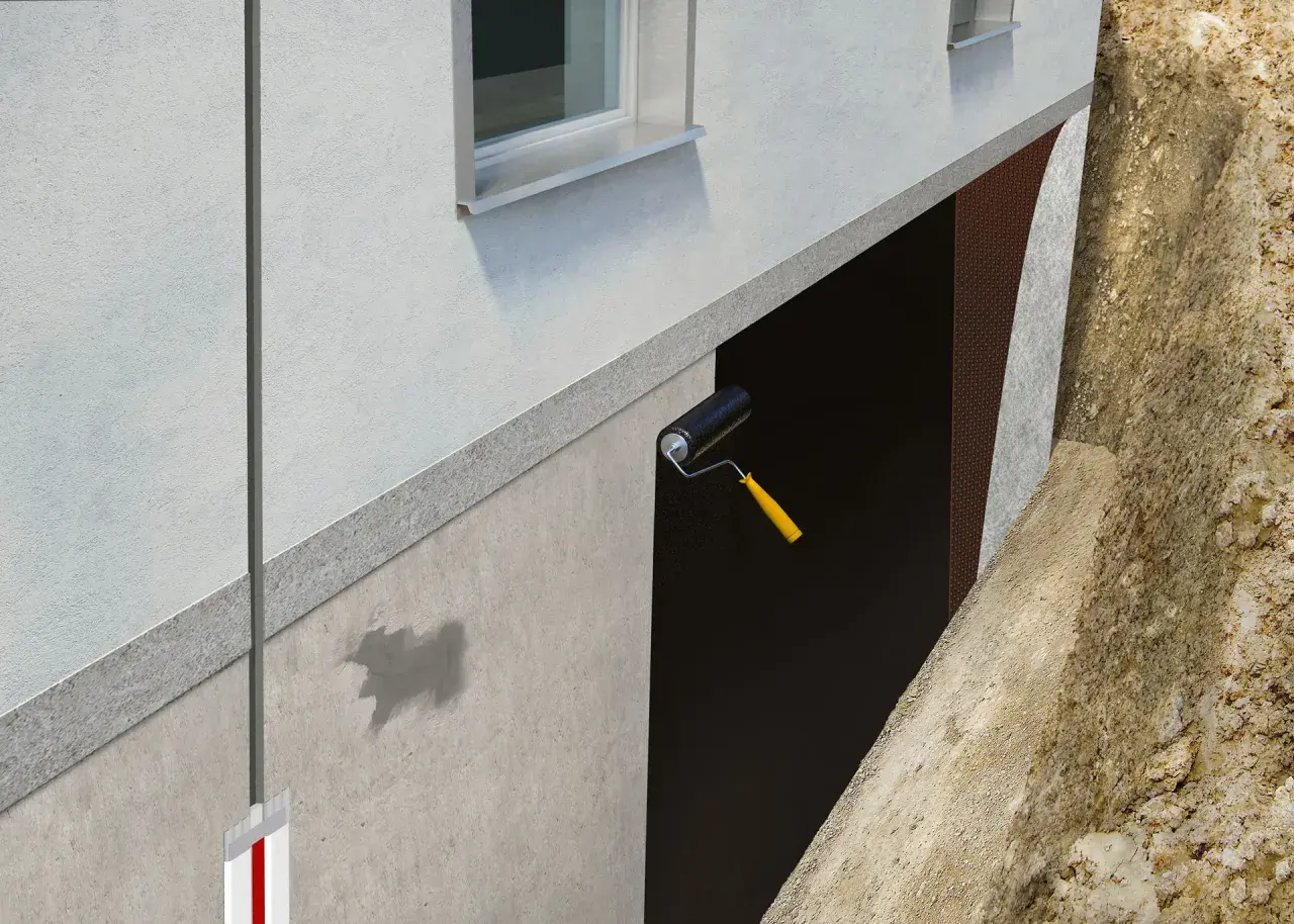 Aplicación de rodillo para impermeabilizar muros enterrados. Se ve la protección de la pared y la tierra excavada.