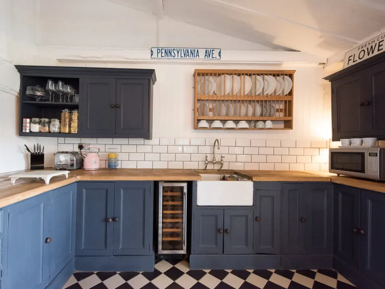 Cocina reformada sin obras: armarios azul marino, encimera de madera, fregadero blanco y suelo de baldosas a cuadros.