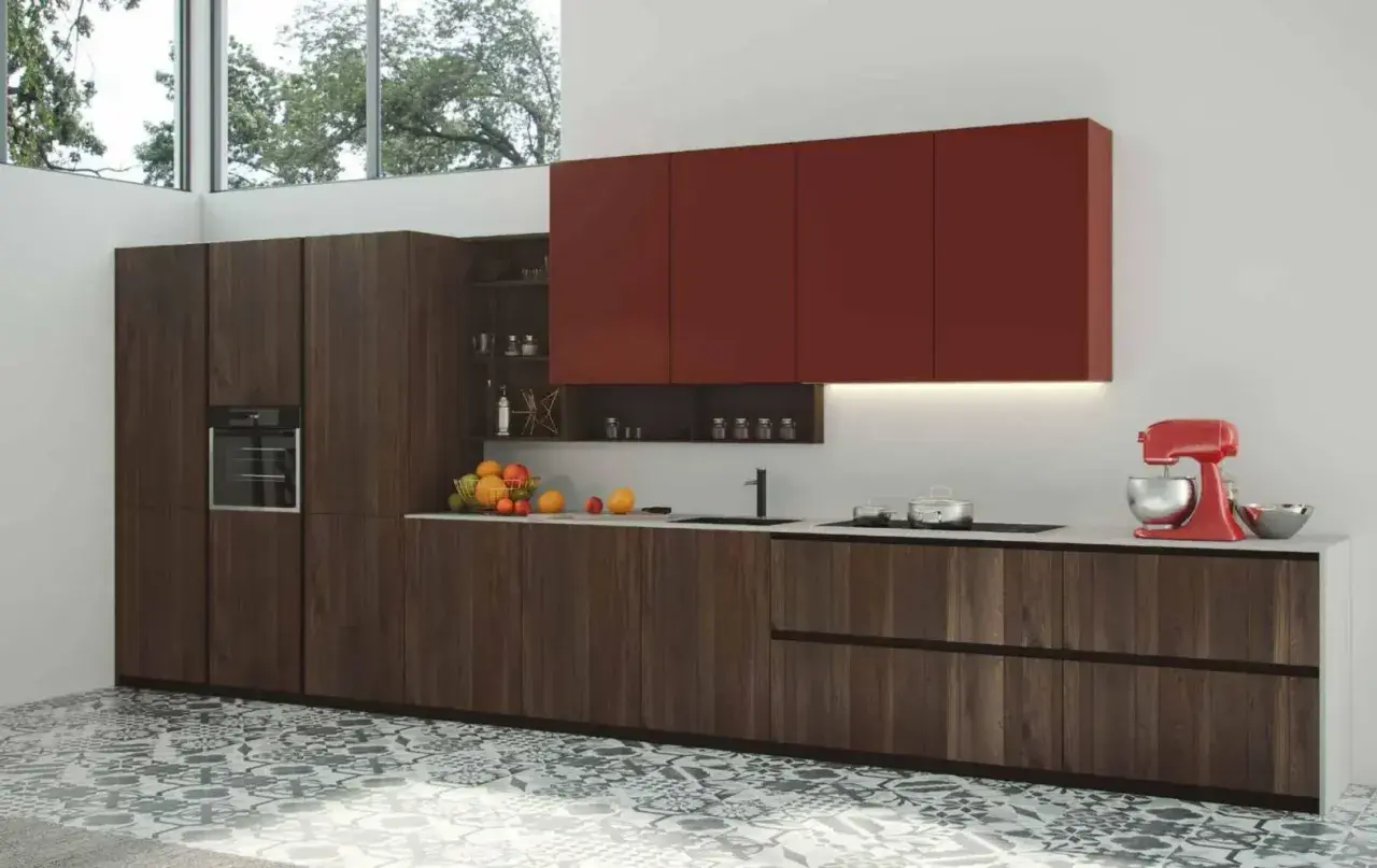 Modernos diseños de cocinas con gabinetes de madera oscura, encimeras blancas y gabinetes superiores rojos vibrantes. Una batidora roja y frutas añaden color.