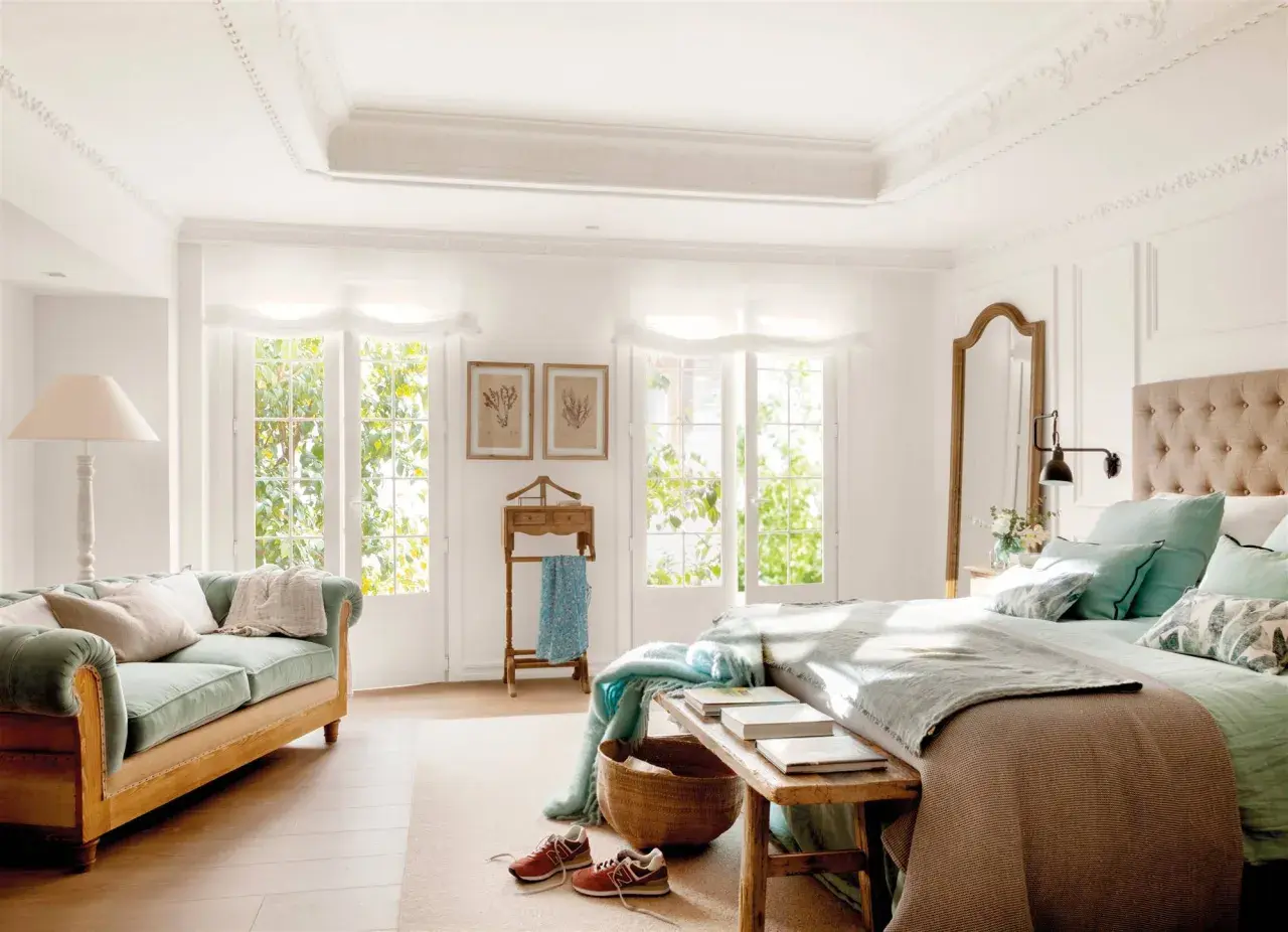 Ideas dormitorio matrimonio: cama con cabecero tapizado, sofá verde, espejo de cuerpo entero y ventanas con luz natural.