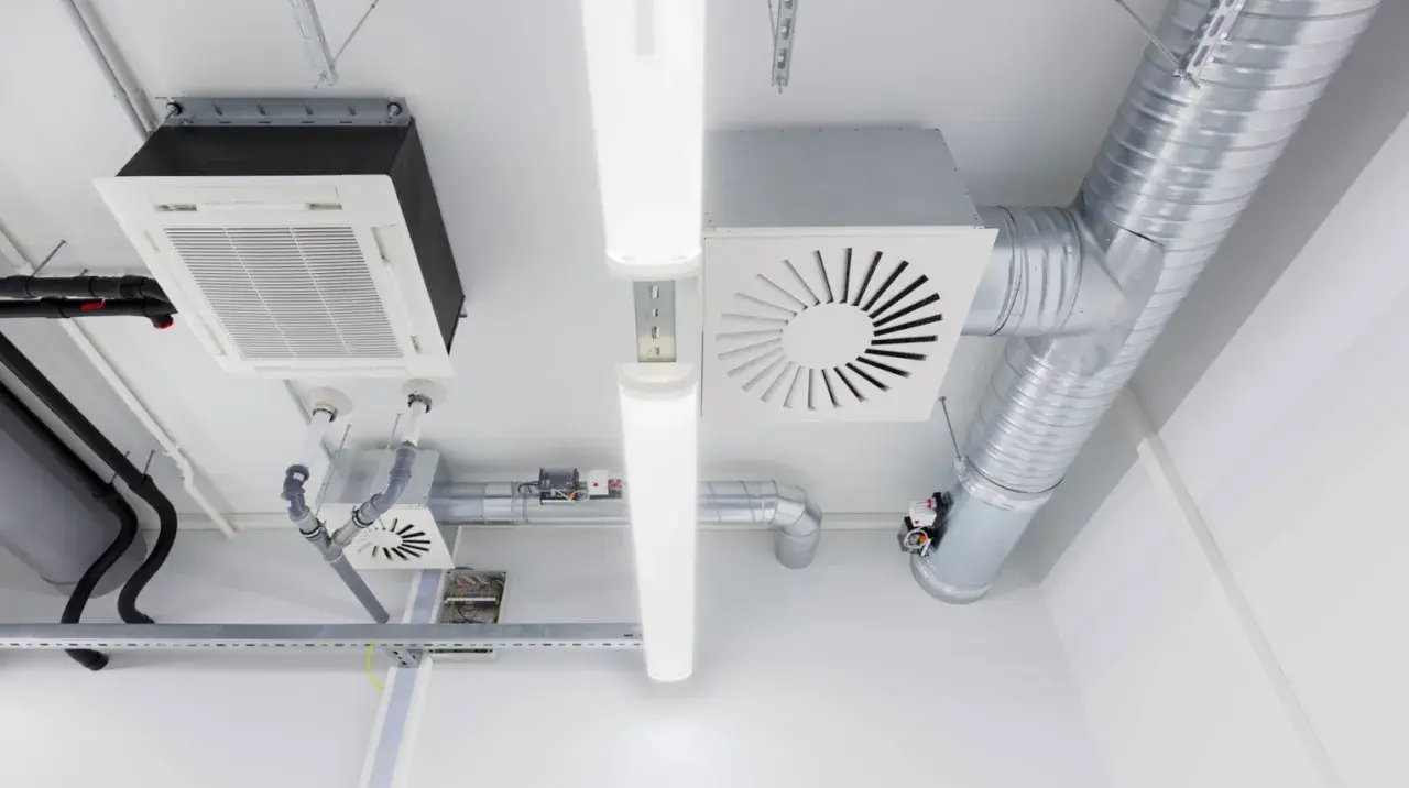 Sistema de ventilación mecánica para vivienda con conductos metálicos, unidades de aire acondicionado y luces LED en el techo.