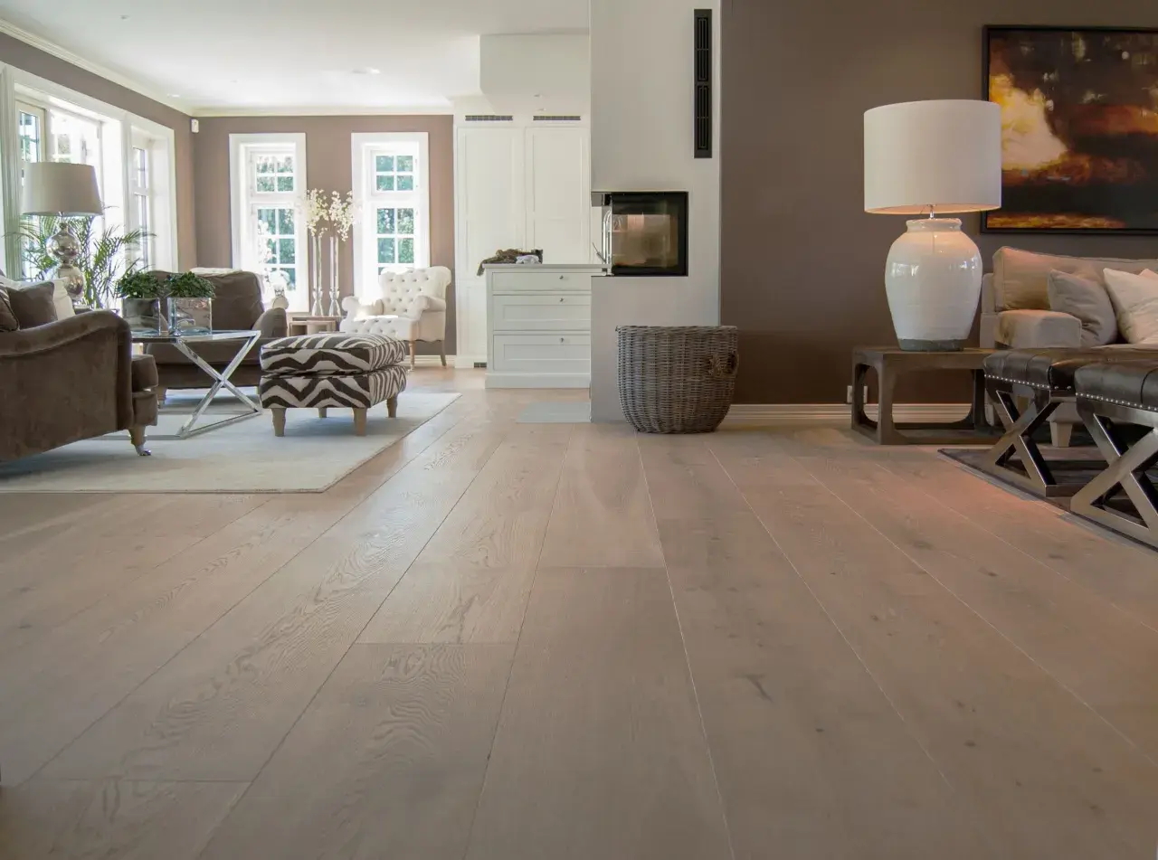 Amplio salón con chimenea y muebles elegantes, destacando los diversos tipos de parquet de madera clara que cubren el suelo.